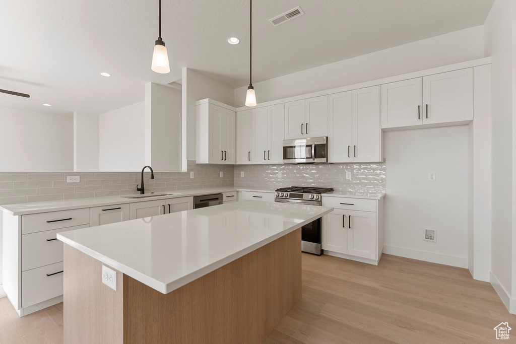 Kitchen featuring visible vents, a center island, a sink, appliances with stainless steel finishes, and backsplash