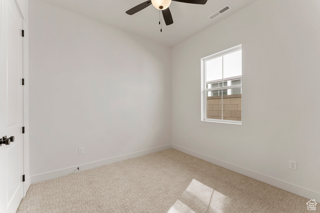 Carpeted empty room featuring baseboards, ceiling fan, and visible vents