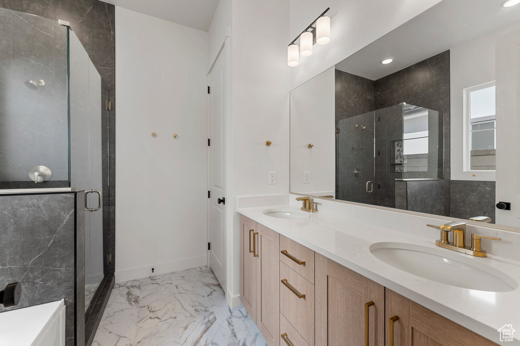 Bathroom featuring double vanity, a sink, marble finish floor, and a stall shower