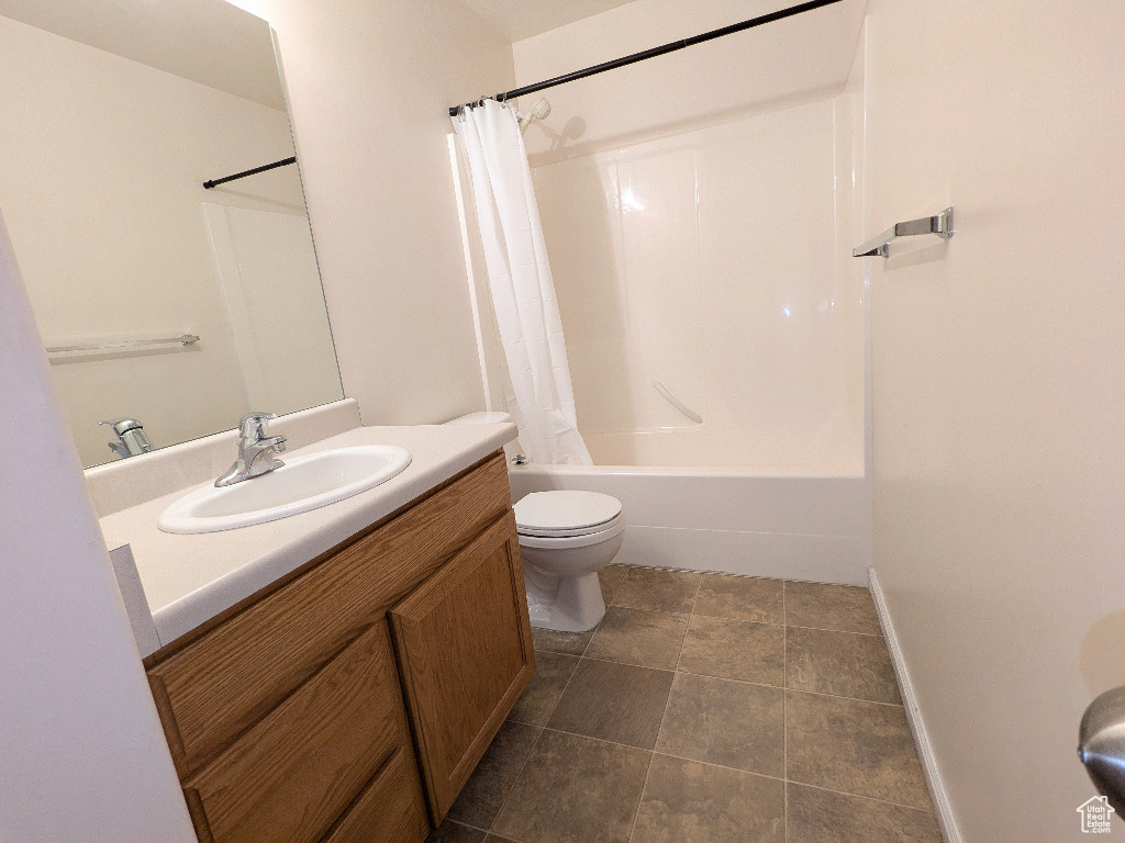 Full bath with vanity, baseboards, shower / bath combo, and toilet