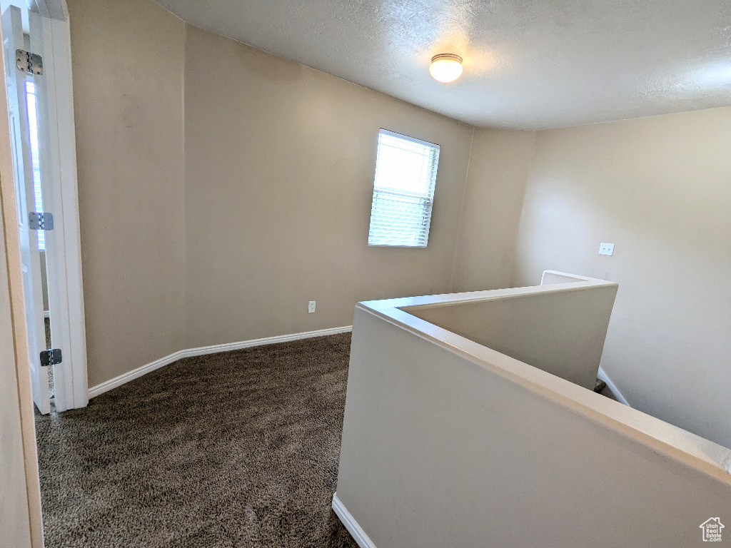 Corridor featuring baseboards, dark carpet, and an upstairs landing
