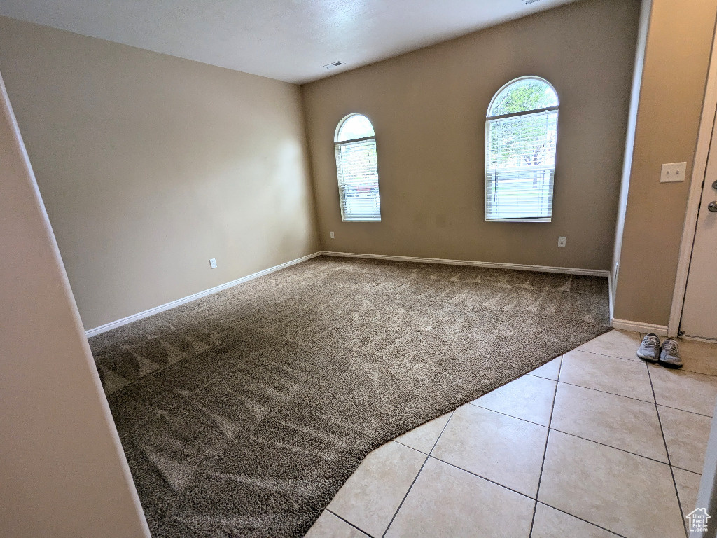 Spare room featuring baseboards, carpet, and tile patterned floors