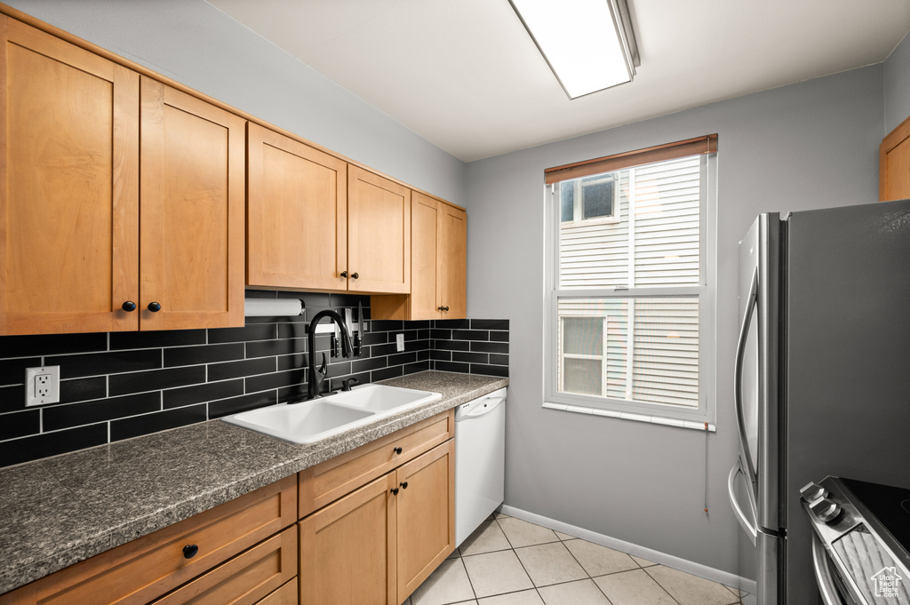 Kitchen featuring freestanding refrigerator, decorative backsplash, stove, a sink, and dishwasher