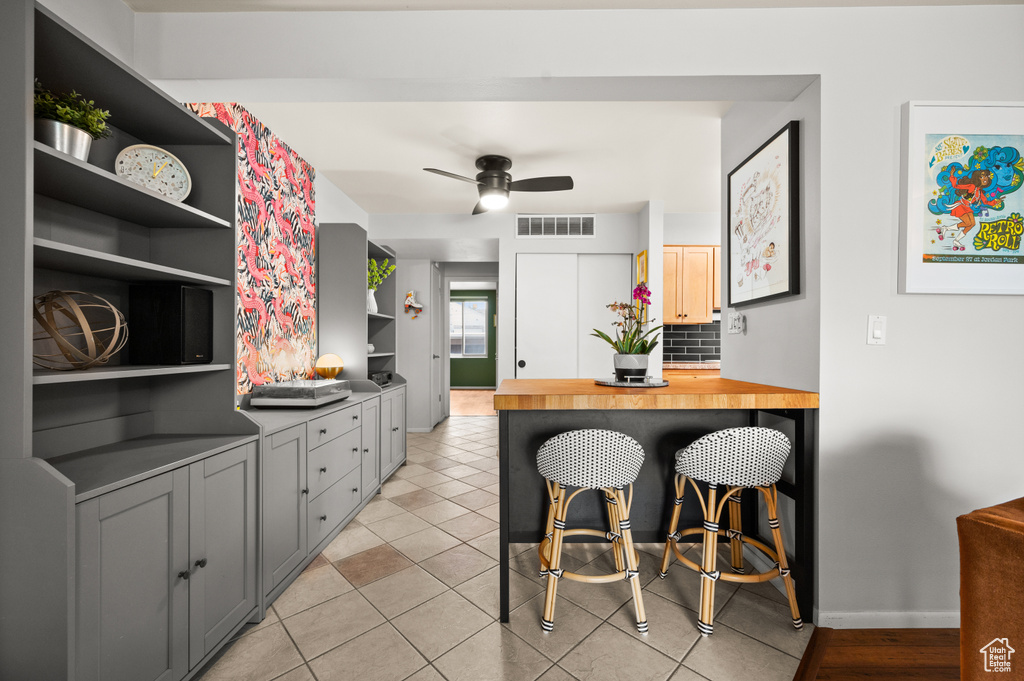 Kitchen featuring light tile patterned flooring, open shelves, ceiling fan, baseboards, and visible vents