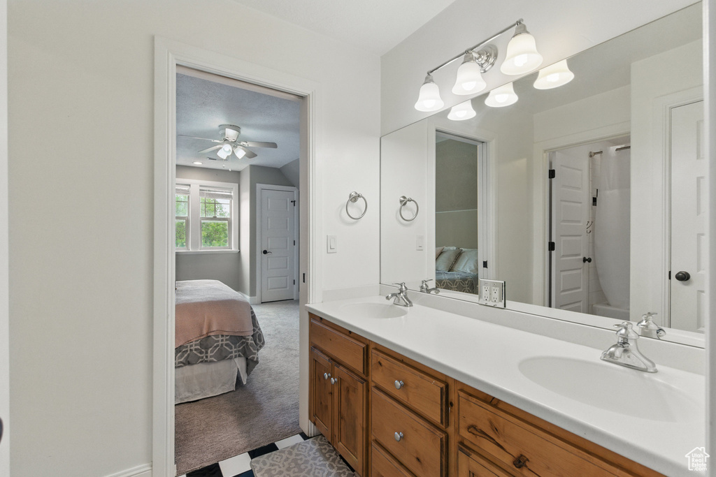Full bath featuring double vanity, a ceiling fan, a sink, baseboards, and ensuite bathroom