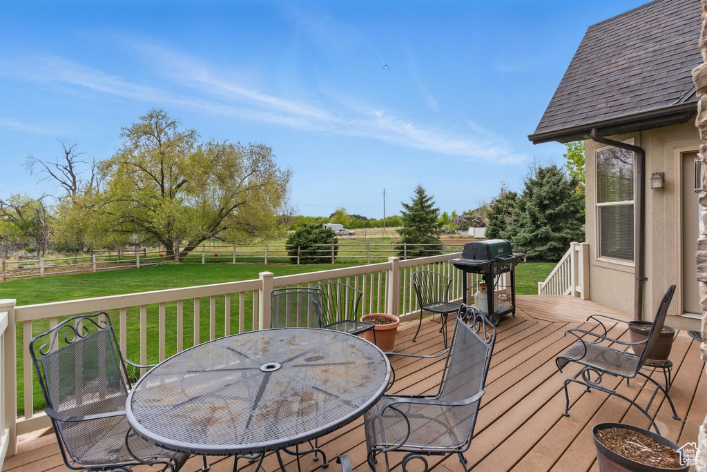 Wooden deck featuring grilling area, a yard, outdoor dining area, and a fenced backyard