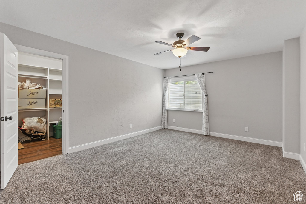 Carpeted spare room featuring a ceiling fan and baseboards