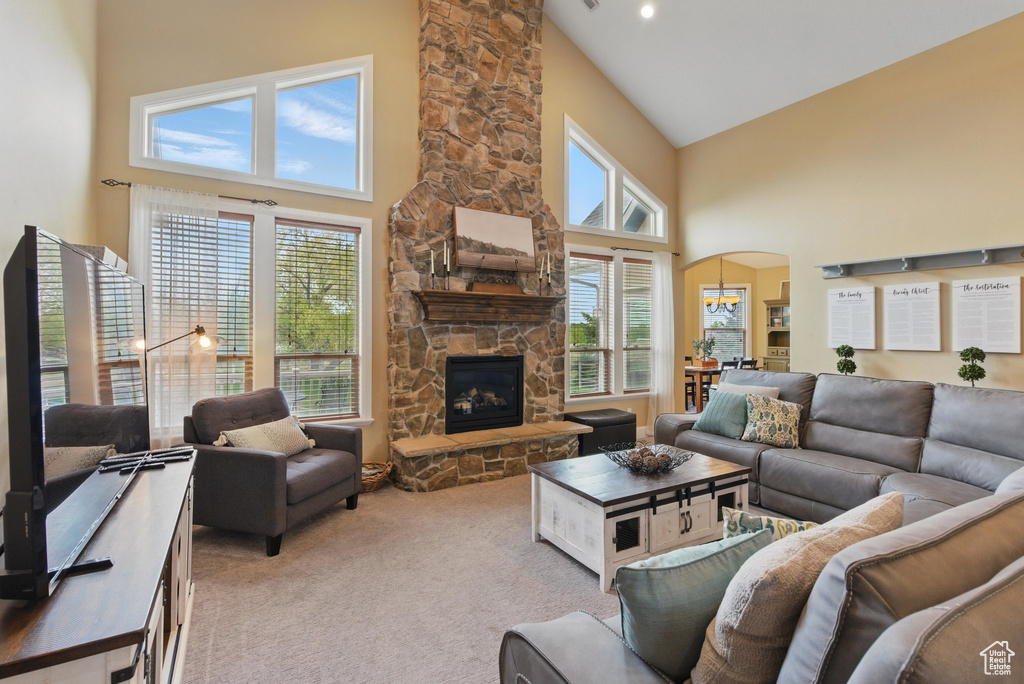 Living room with a stone fireplace, arched walkways, light carpet, and high vaulted ceiling