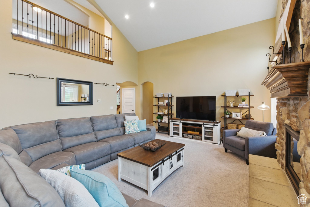 Living area featuring a fireplace, light carpet, high vaulted ceiling, recessed lighting, and arched walkways