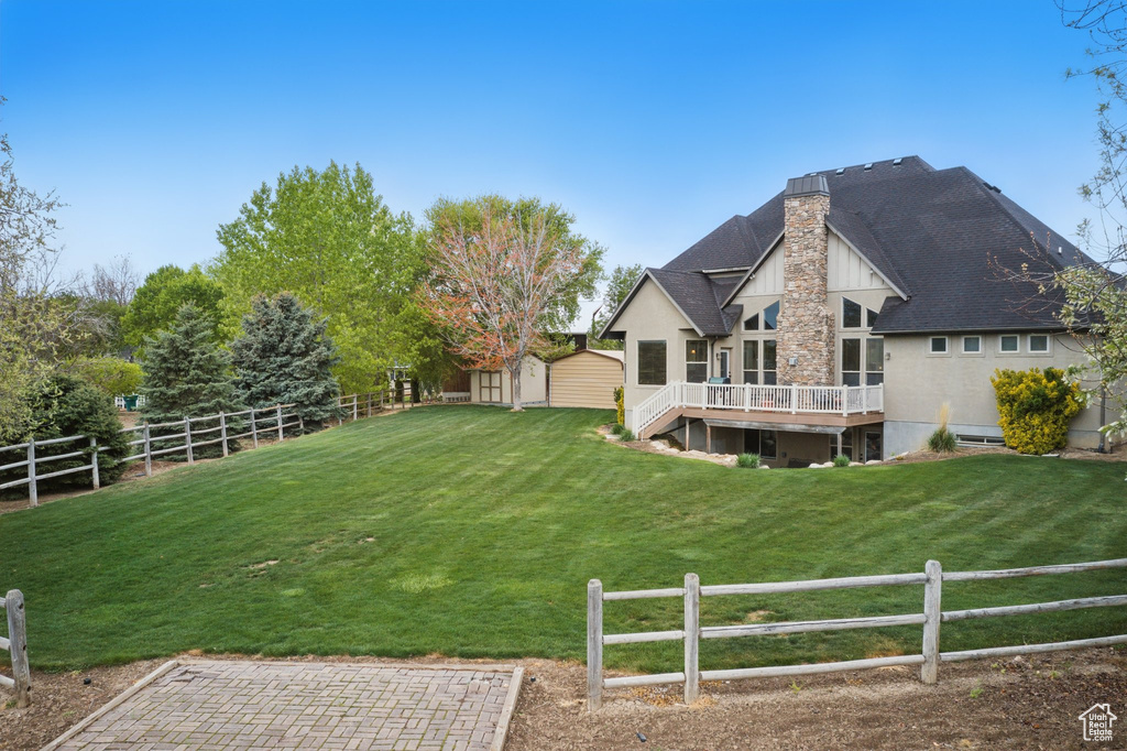 View of yard featuring a fenced backyard, a wooden deck, an outdoor structure, and a storage shed