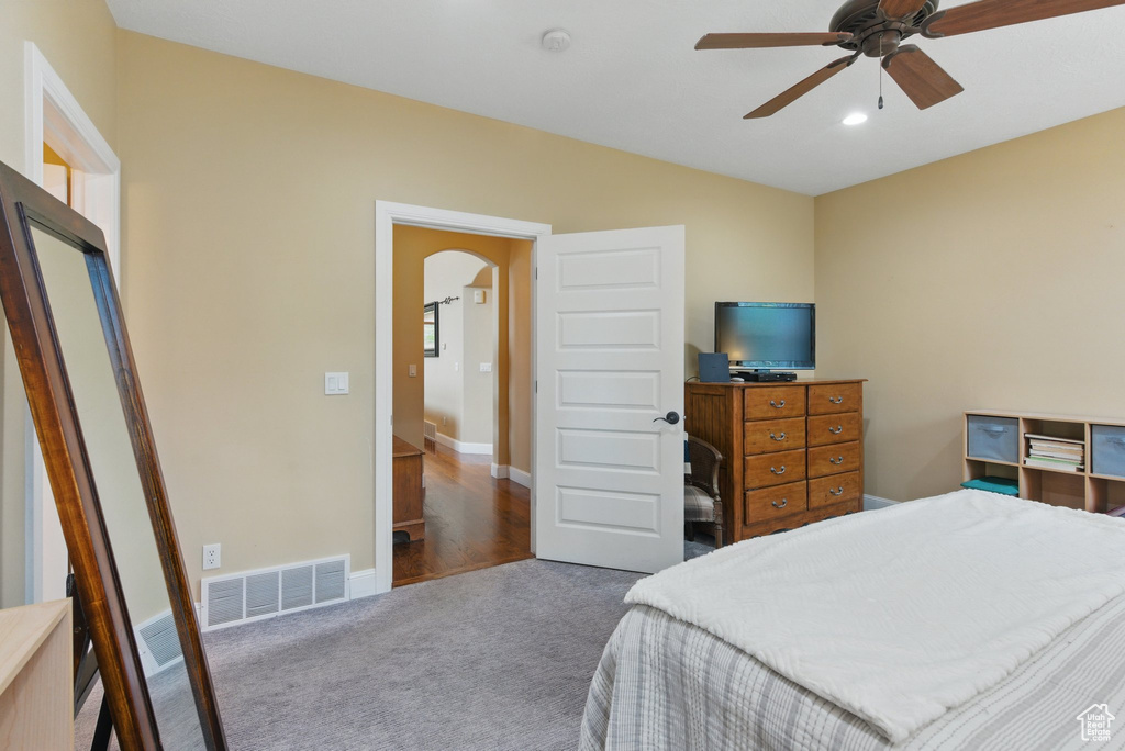 Carpeted bedroom featuring arched walkways, ceiling fan, and visible vents