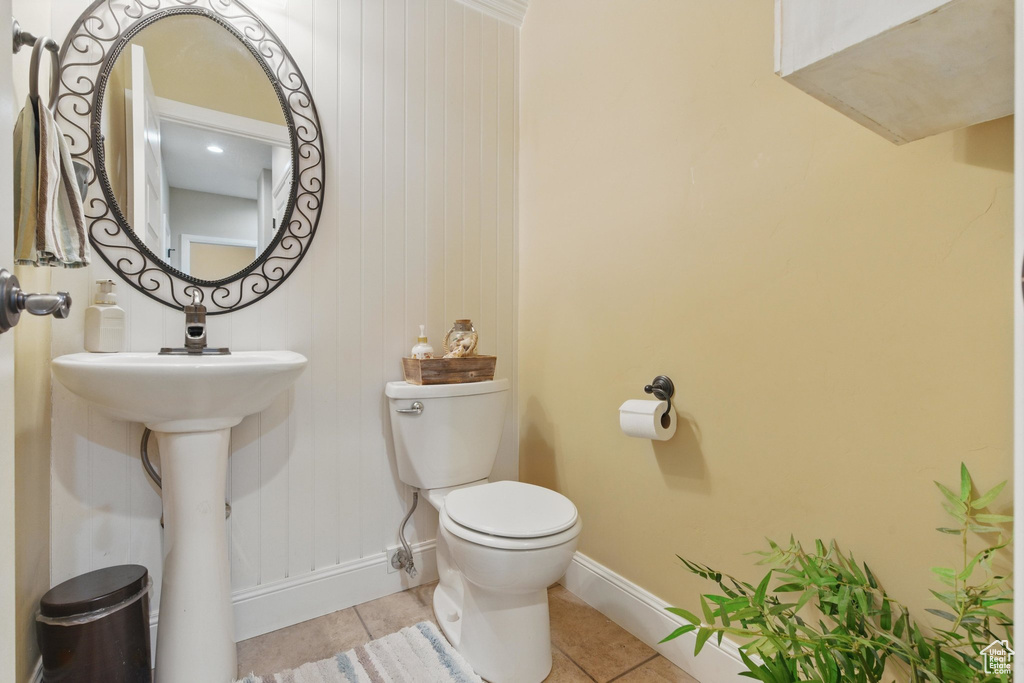 Half bathroom featuring toilet, tile patterned floors, a sink, and baseboards