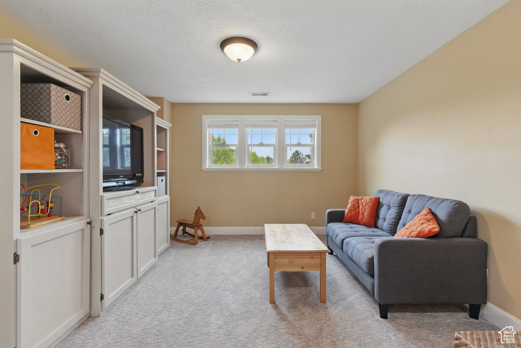 Living area with baseboards, light carpet, and visible vents
