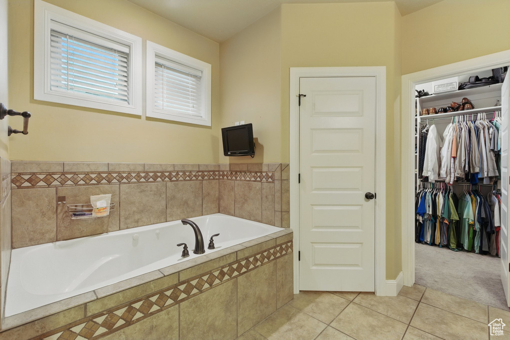 Bathroom with tile patterned floors, a walk in closet, and a garden tub