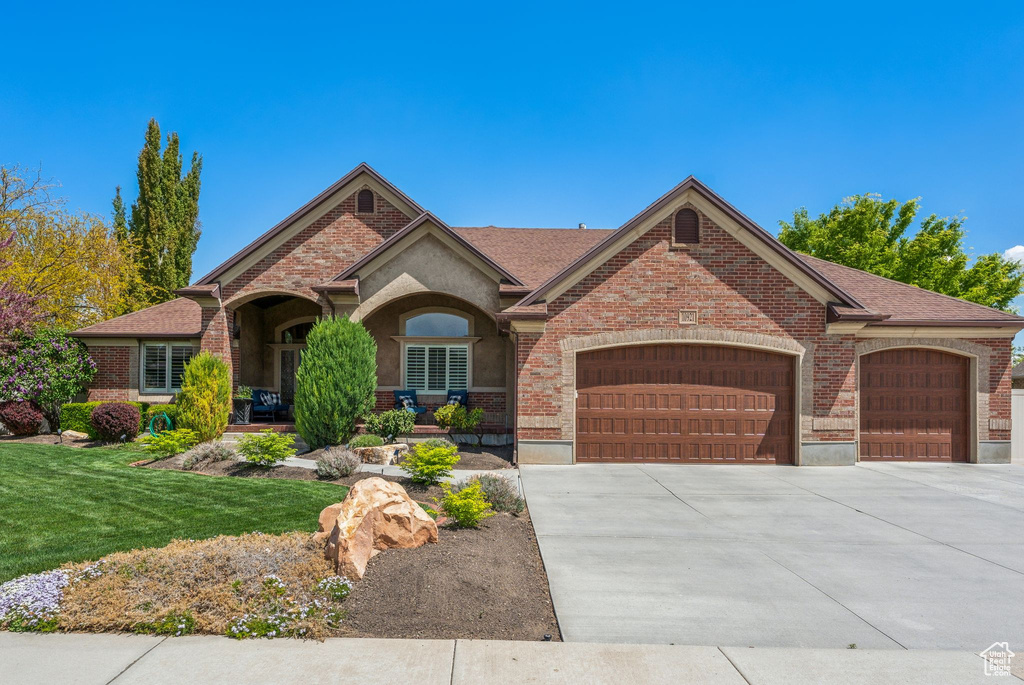 Ranch-style home featuring brick siding, an attached garage, driveway, and a front yard