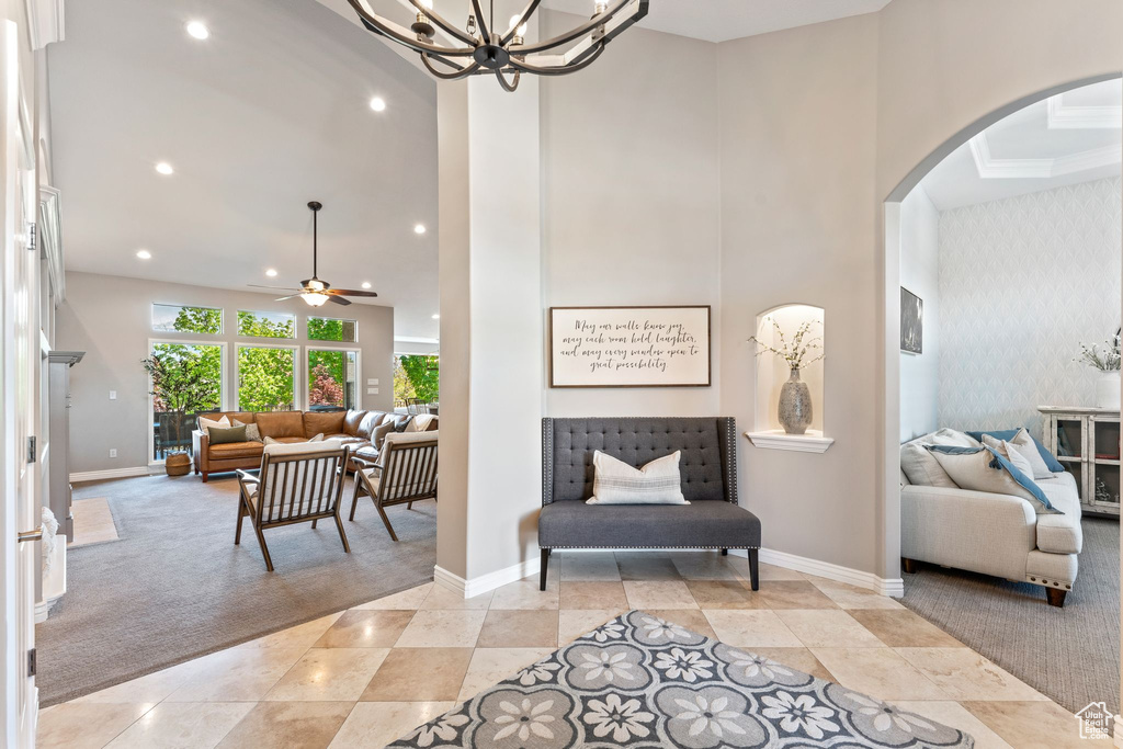 Interior space featuring arched walkways, baseboards, recessed lighting, and ceiling fan with notable chandelier
