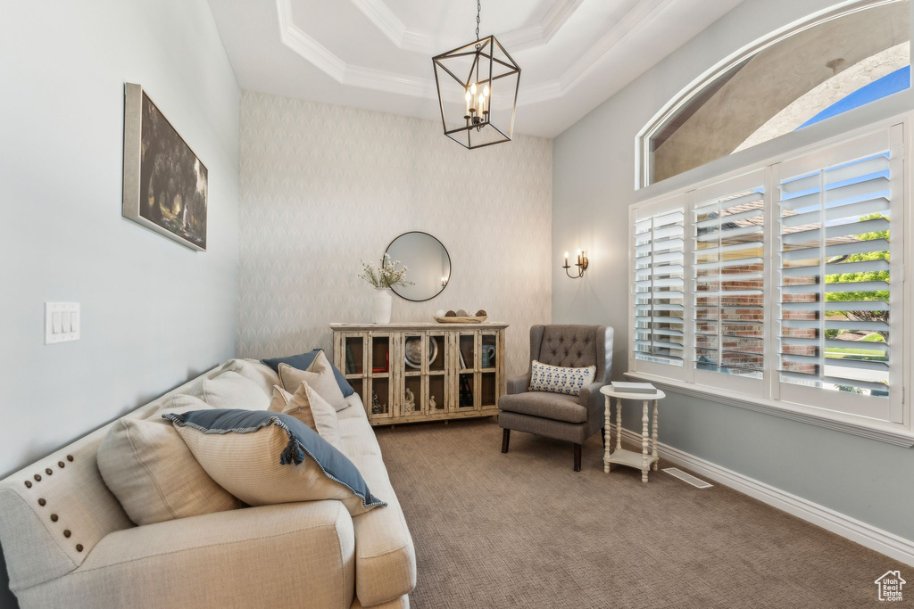 Living area featuring an inviting chandelier, crown molding, carpet floors, visible vents, and a tray ceiling