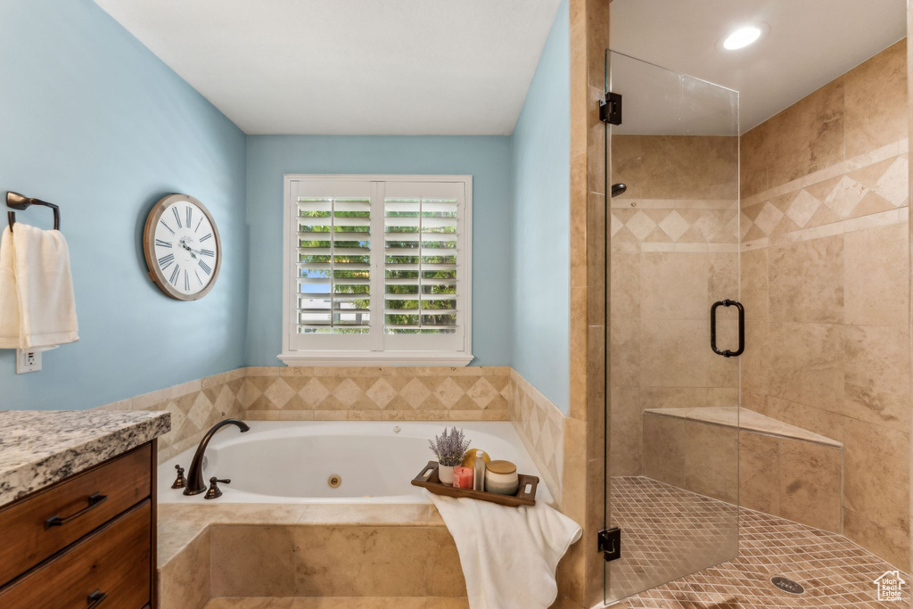 Bathroom featuring vanity, a jetted tub, and a stall shower