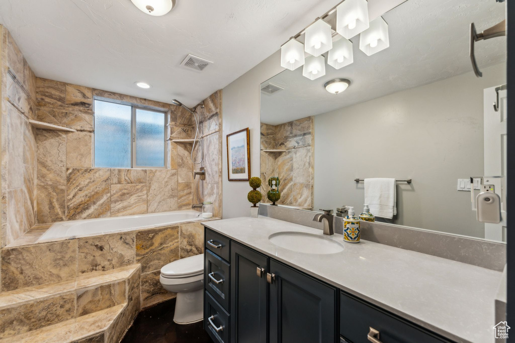 Full bathroom with toilet, tiled shower / bath, visible vents, and vanity