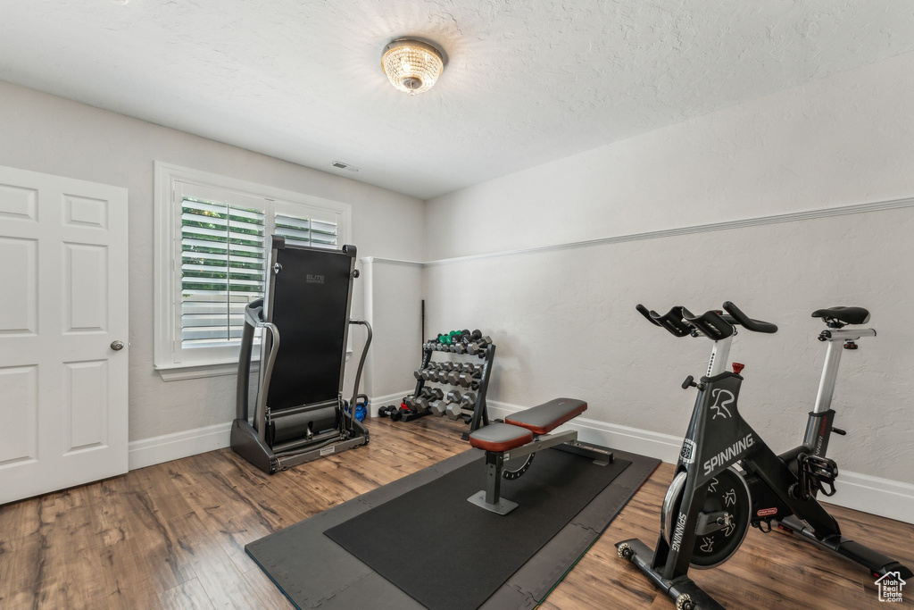 Workout room featuring baseboards, visible vents, and wood finished floors