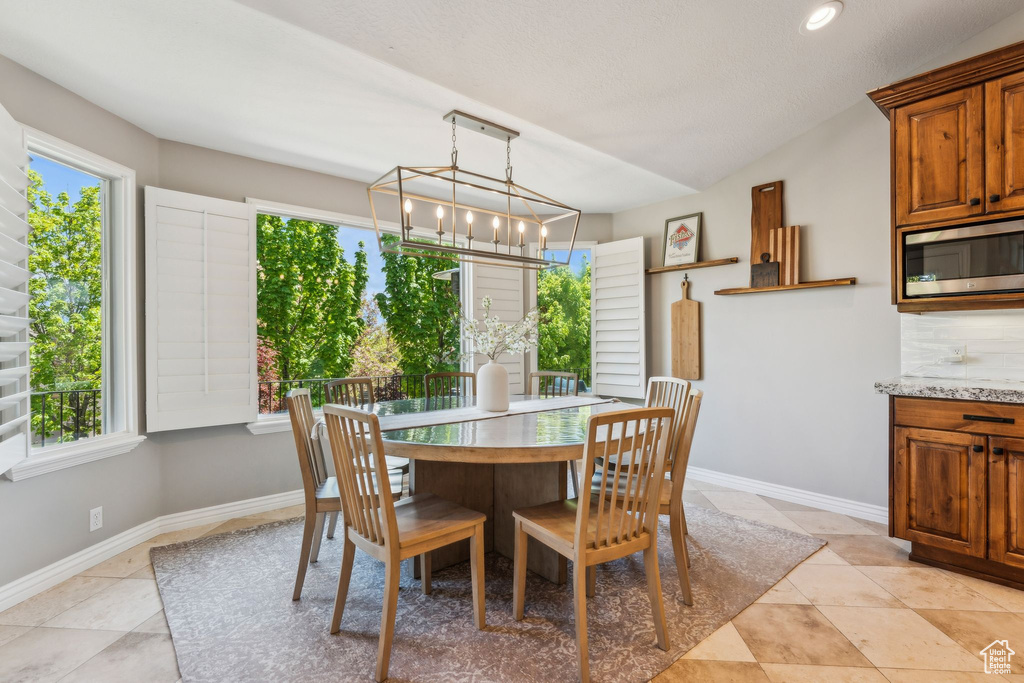 Dining room featuring an inviting chandelier, light tile patterned floors, and baseboards