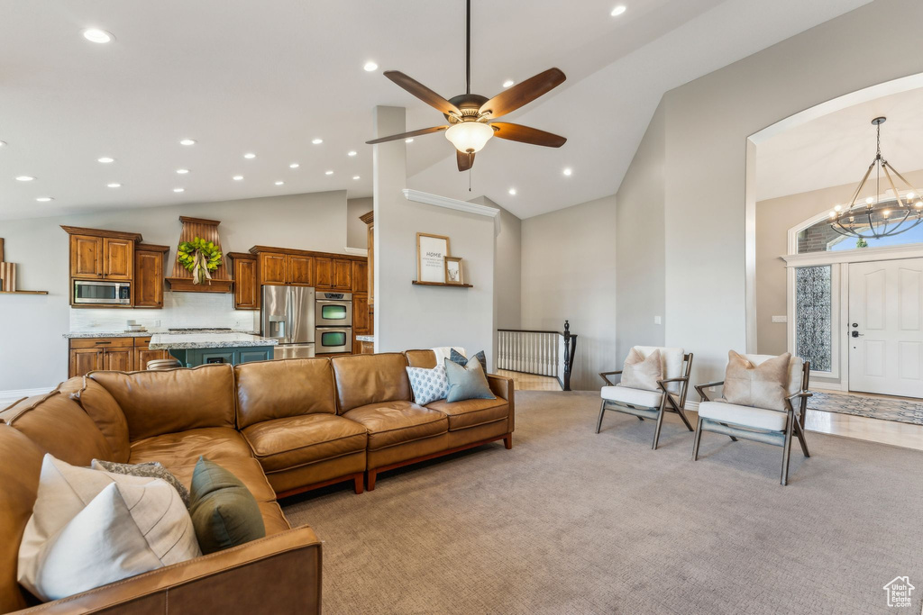 Living room featuring recessed lighting, high vaulted ceiling, light carpet, and ceiling fan with notable chandelier