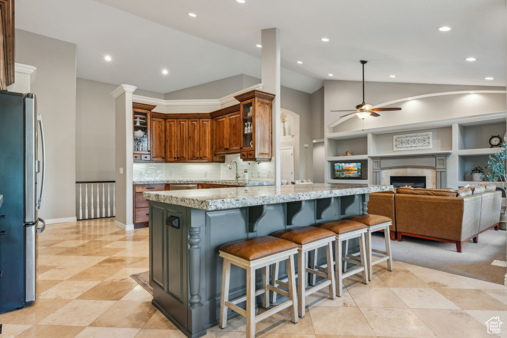 Kitchen with a ceiling fan, light stone countertops, vaulted ceiling, freestanding refrigerator, and recessed lighting