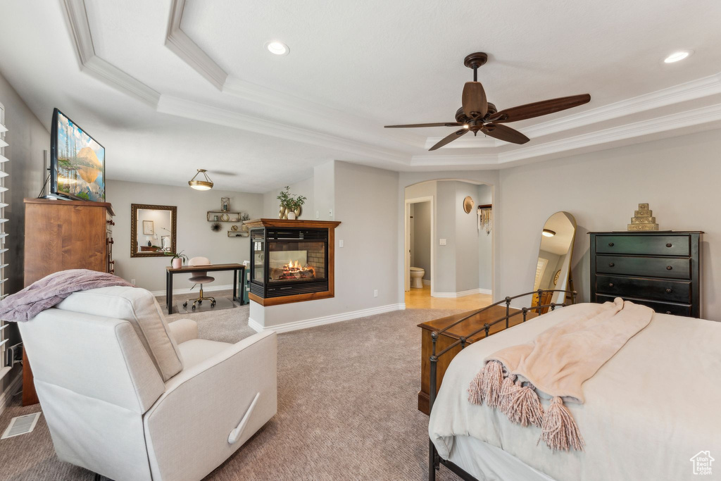 Bedroom featuring crown molding, arched walkways, a raised ceiling, and carpet floors