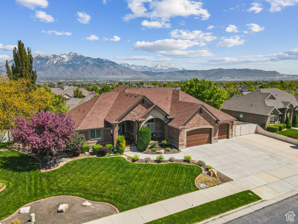 View of front of house featuring a front yard, brick siding, a mountain view, concrete driveway, and an attached garage