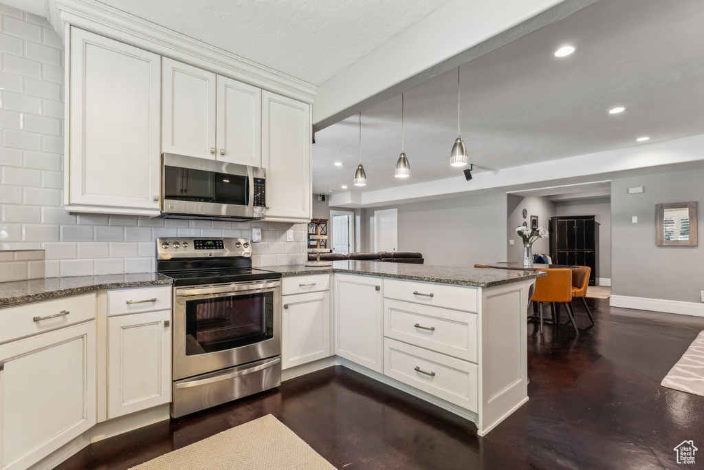 Kitchen featuring decorative backsplash, appliances with stainless steel finishes, baseboards, a peninsula, and recessed lighting