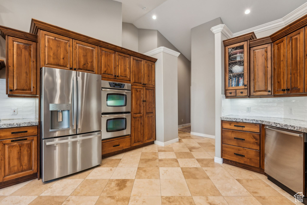Kitchen featuring backsplash, baseboards, appliances with stainless steel finishes, and light stone counters