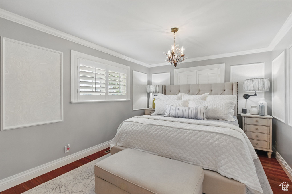 Bedroom featuring baseboards, dark wood finished floors, crown molding, and a chandelier