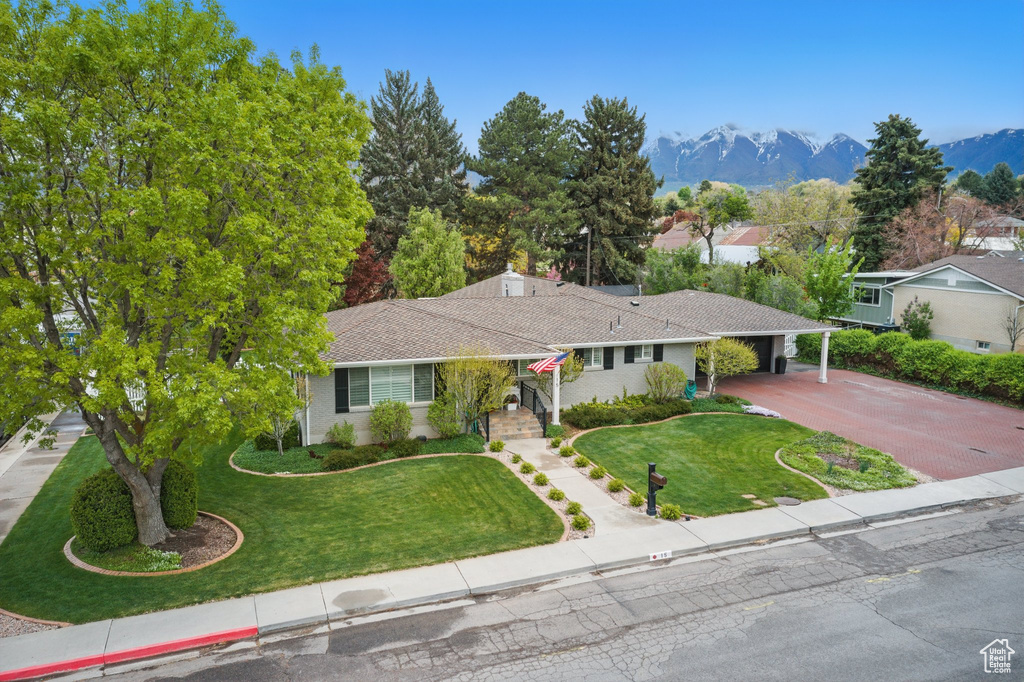 Single story home featuring a mountain view, an attached carport, driveway, and a front yard