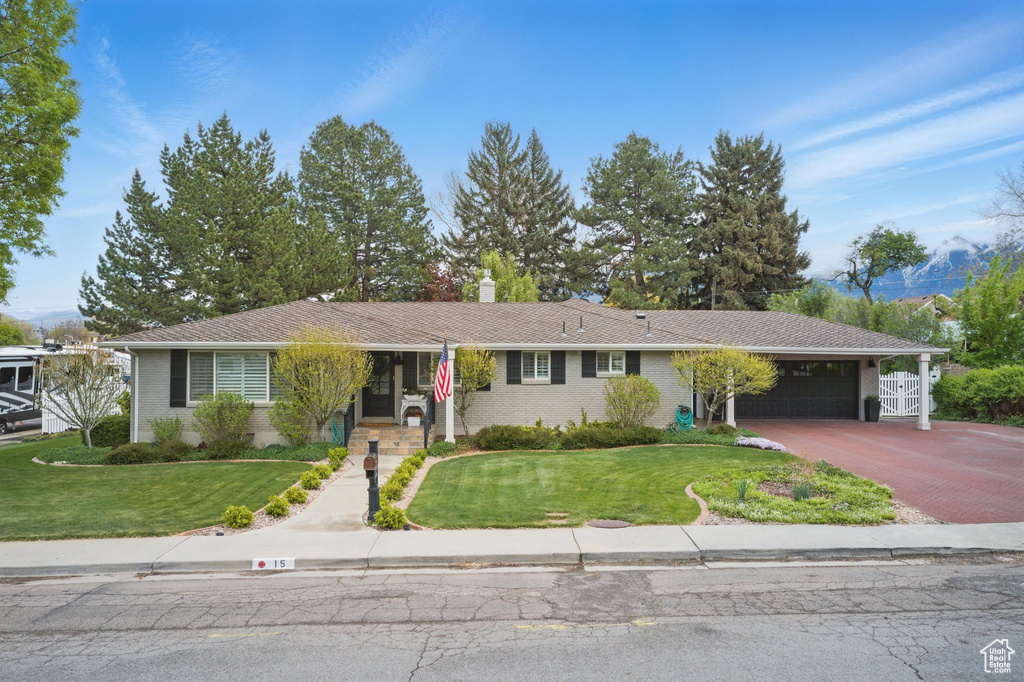 Ranch-style house featuring brick siding, a garage, driveway, and a front yard