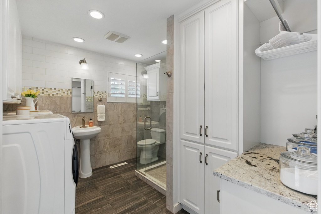 Full bathroom with washer / clothes dryer, visible vents, a shower stall, a sink, and recessed lighting