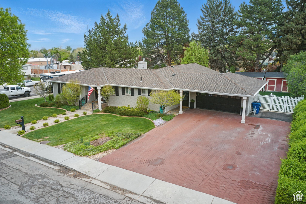 Ranch-style house with fence, a front lawn, a garage, a chimney, and decorative driveway