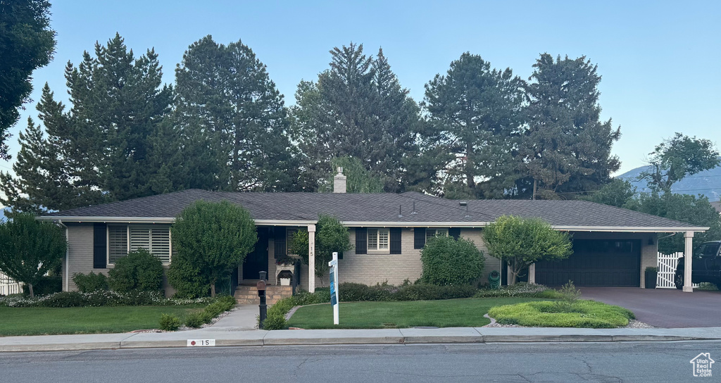View of front of house featuring an attached garage, a front yard, a chimney, and asphalt driveway