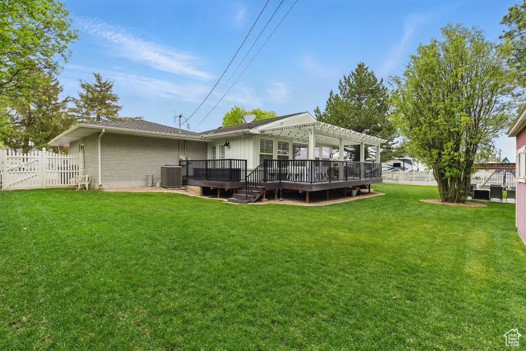 Rear view of house featuring a wooden deck, brick siding, fence, a yard, and a pergola