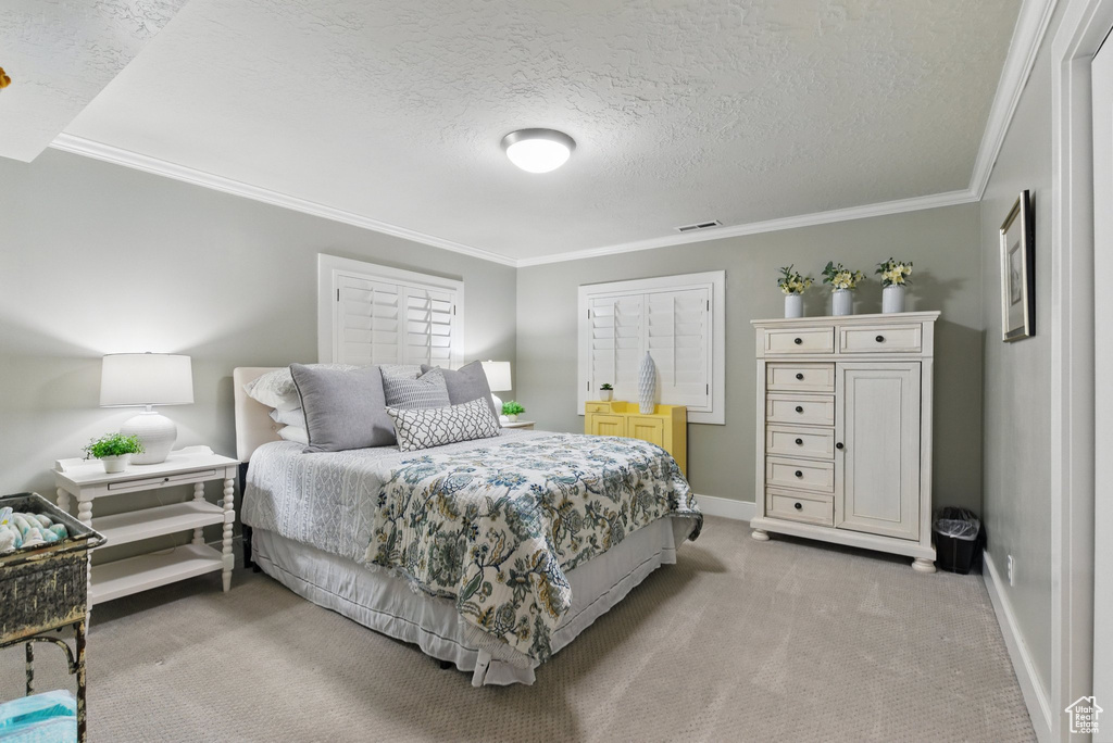 Bedroom featuring crown molding, light carpet, a textured ceiling, and visible vents