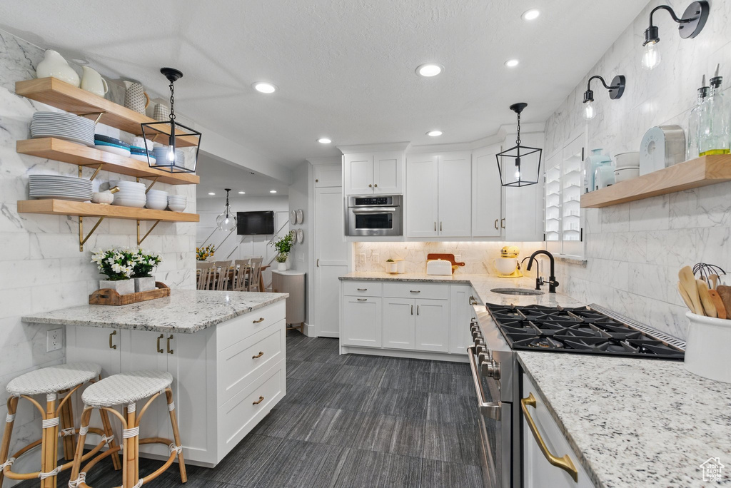 Kitchen featuring open shelves, appliances with stainless steel finishes, a sink, white cabinetry, and recessed lighting