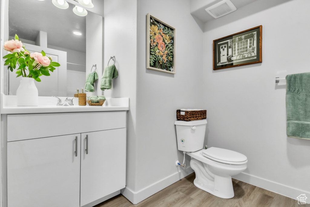 Bathroom with baseboards, wood finished floors, toilet, and vanity