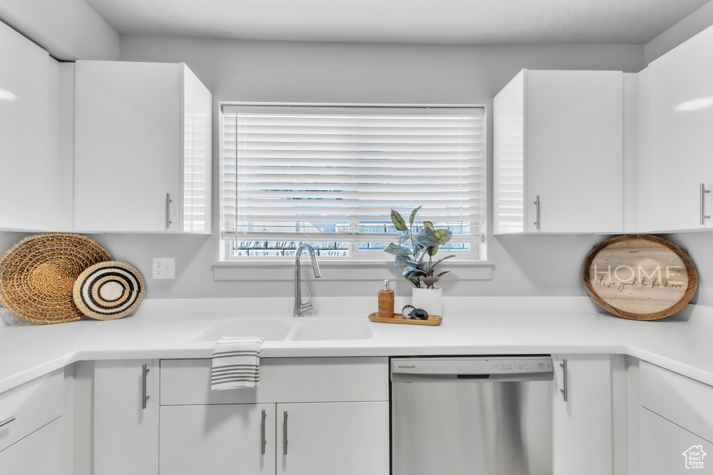 Kitchen featuring a sink, white cabinetry, dishwasher, and a healthy amount of sunlight
