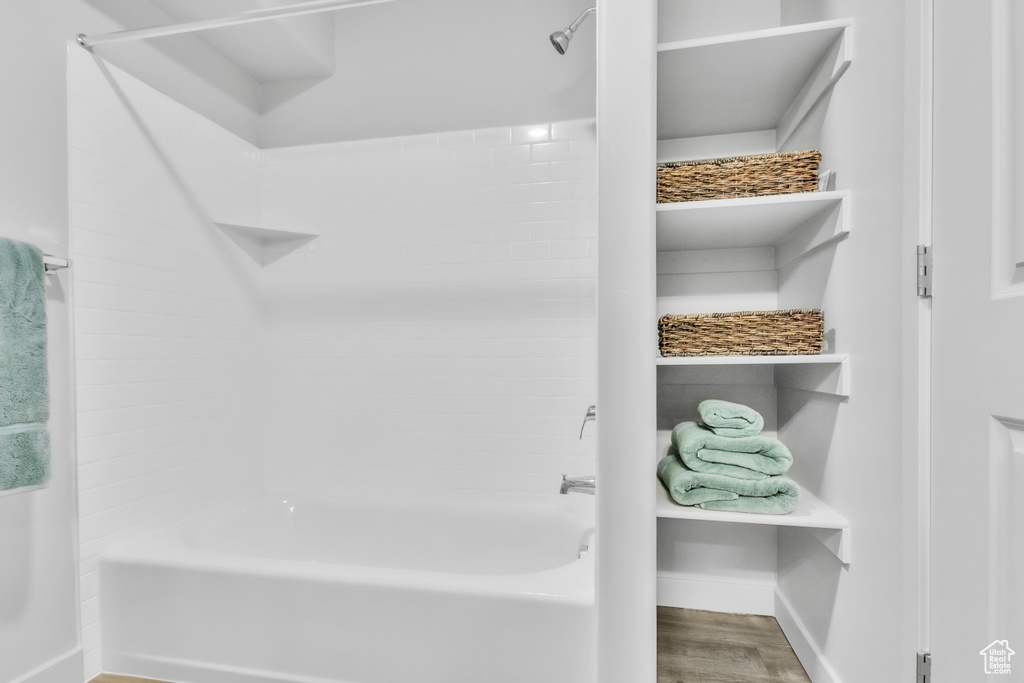 Full bath with baseboards, bathing tub / shower combination, and wood finished floors