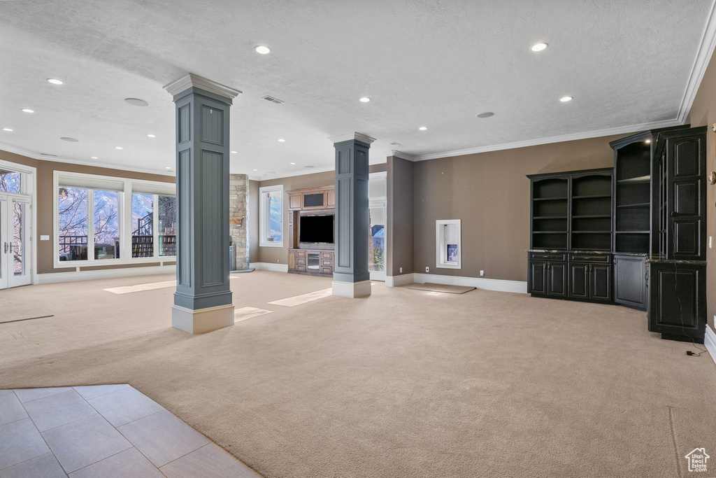 Unfurnished living room featuring crown molding, baseboards, ornate columns, light carpet, and recessed lighting