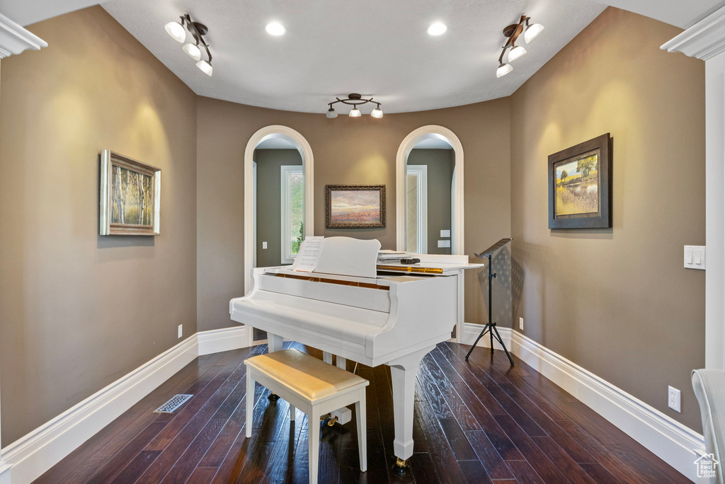Living area featuring arched walkways, baseboards, rail lighting, and visible vents