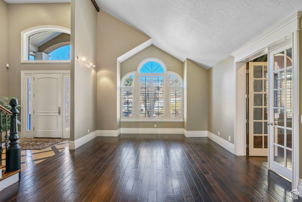 Foyer entrance with baseboards, french doors, hardwood / wood-style flooring, and lofted ceiling