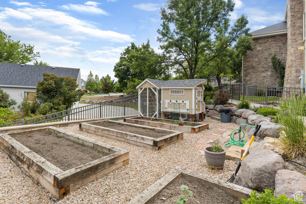 View of yard with fence, an outbuilding, and a vegetable garden
