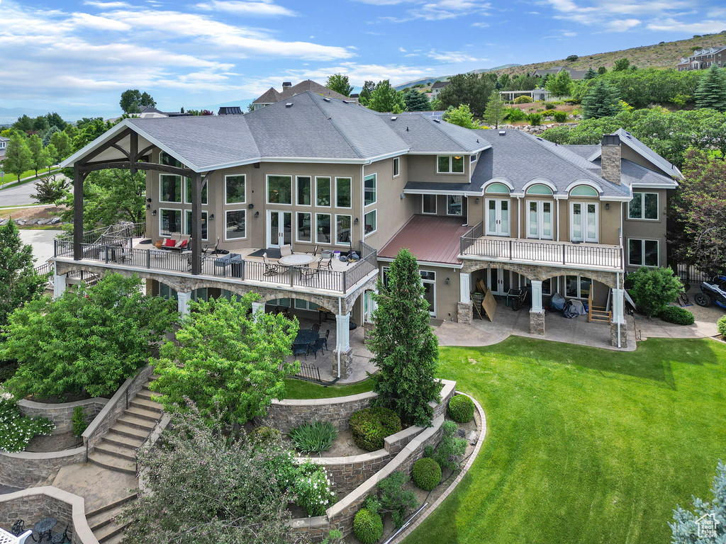 Rear view of property featuring roof with shingles, stairway, a chimney, a patio, and a yard