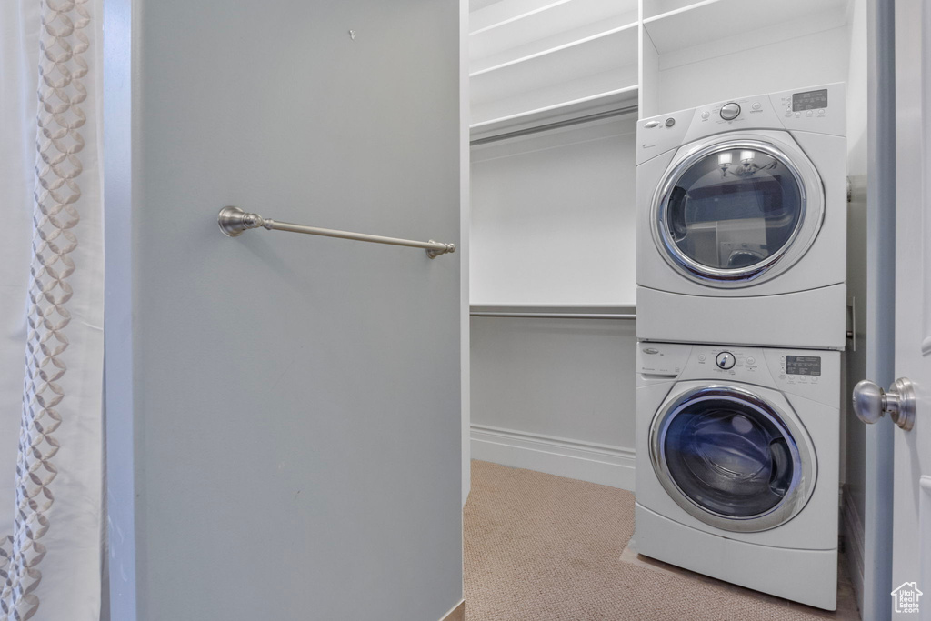 Washroom with laundry area, carpet flooring, baseboards, and stacked washer / dryer