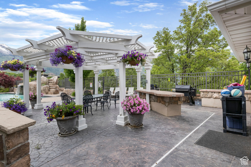 View of patio featuring outdoor dining area, grilling area, fence, and a pergola